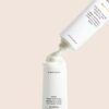 En tube med Innersense Hydrating Hair Mask - Repair & Revitalize 177ml med hætten fjernet, og dispenserer en klat af produktet. Røret er hvidt med sort tekst.