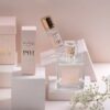 Udstilling af Ærlig P01 - Eau de Parfum 100 ml glasflaske, med sprayflaske, rulleflaske og emballagekasser, med en kvist hvide blomster.