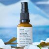 En flaske Evolve Organic Beauty Age Defying Lifting Serum 30 ml siddende på en bunke is.