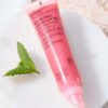 En tube Evolve Organic Beauty Bio-Retinol Glossy Lip Oil 15 ml med et mynteblad ved siden af.