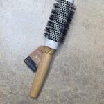 En Olivia Garden Bamboo Touch Blowout rundbørste termisk 23 mm hårbørste på betongulv.