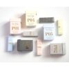 Forskellige Ærlig P05 – Eau de Parfum 15 ml glasflaske Roll on TRAVEL æsker mærket med forskellige koder (P01, P02 osv.) vises på hvid baggrund. Farverne på kasserne inkluderer pink, guld, sort, lyseblå og beige.