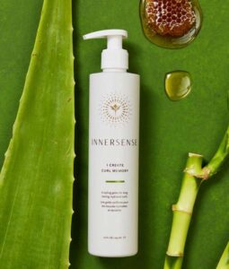 En flaske Innersense I Create Curl Memory - Hydrating Styling Gel 295 ml på en grøn baggrund.